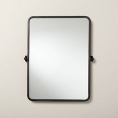 a mirror that is on the wall with a black frame and metal trim around it