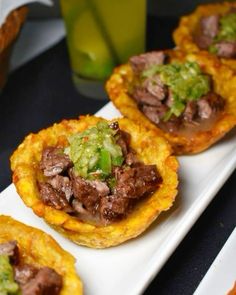 small appetizers with meat and veggies in them on a white plate