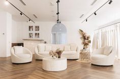 a living room filled with white furniture and wooden floors