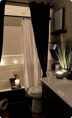 a white toilet sitting next to a bath tub in a bathroom under a black and white shower curtain