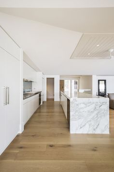 a large kitchen with white cabinets and marble counter tops, along with hardwood flooring