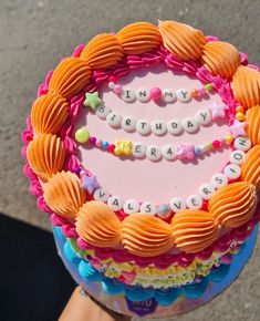 a decorated birthday cake with the words happy birthday written on it, in front of a person's hand