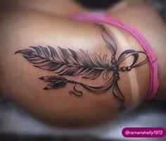 a woman's stomach with a feather tattoo on it