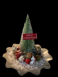 a small christmas tree sitting on top of a snow covered tray with candy and candies