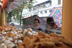 a woman holding an umbrella looking at pastries