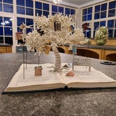 an open book sitting on top of a table next to a vase filled with flowers