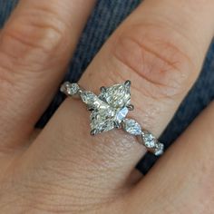 a woman's hand with a diamond ring on top of her finger and an engagement band