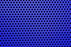 a blue metal background with holes in the center and black circles on it's surface