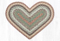 a heart shaped rug on top of a white wooden floor with a green and brown pattern