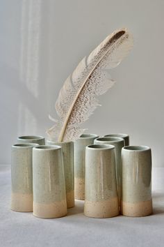 a white feather is sitting on top of some cups