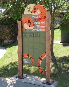 a sign with an orange and black animal on it's side in front of some trees