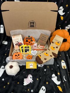 an open box filled with halloween treats on top of a black cloth covered tablecloth