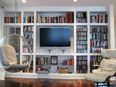 a living room filled with lots of furniture and a flat screen tv on top of a book shelf