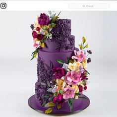 a three tiered purple cake with flowers on top