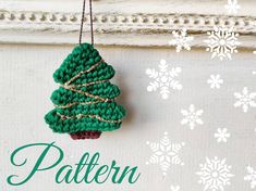 a crocheted christmas tree ornament hanging on a wall with snowflakes