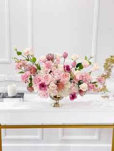 a vase filled with pink and white flowers sitting on top of a table next to a mirror