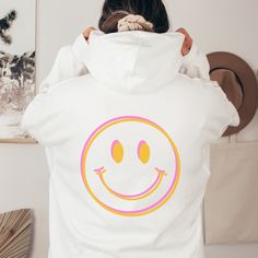 Spread some good vibes in your over-sized hoodie with a giant double vision smiley face printed on the back. Exclusively designed by Parcel 23. Direct to garment printed in the USA (this is not a transfer, it's the real deal). Select your size and favorite color option, and we'll have it produced and delivered in about a week. Gildan Unisex Heavyweight Blend Hoodie. Classic fit, Unisex sizing.  Size up for a relaxed look. Size down if you prefer a sporty, fitted look. 50% cotton, 50% polyester Soft and warm. Madde to last a lifetime. Any questions or custom requests, give a shout via Etsy Messages. We're happy to help! BIG THANKS for your consideration to shop small. parcel23.etsy.com Fun Hoodie Sweatshirt With Drawstring Hood, Fun Sweatshirt With Drawstring Hood, Fun Hooded Sweatshirt For Streetwear, Fun Hoodie With Letter Print For Streetwear, Fun Letter Print Hoodie For Streetwear, White Fun Winter Hoodie, Fun White Winter Hoodie, Fun Graphic Print Hoodie Sweatshirt, Fun Graphic Print Hoodie For Streetwear