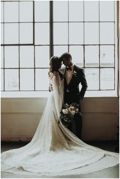 a bride and groom standing in front of a window