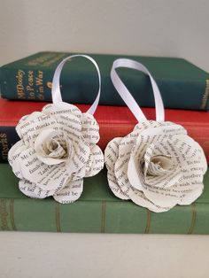 three books stacked on top of each other with two paper roses attached to the book ends