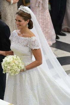 the bride smiles as she walks down the aisle in her wedding dress and tiara