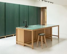 a kitchen with green walls and counter top next to two stools on the floor