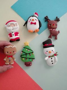 a hand is pointing at christmas decorations on a table next to a penguin and snowman