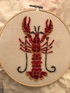 a red lobster embroidered on a white background