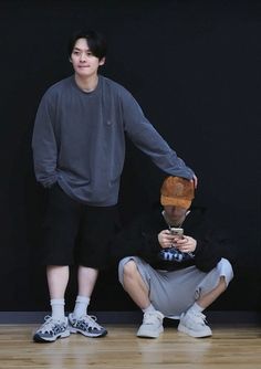 two young men standing next to each other on a wooden floor