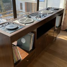 an entertainment center with two turntables and record players on it in front of a window