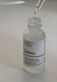 a dropper filled with liquid sitting on top of a white table next to a bottle