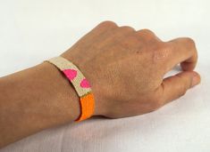 a person's hand with an orange and pink bracelet on their wrist, resting against a white background