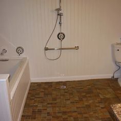 a bath room with a toilet a sink and a shower head mounted to the wall