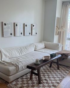 a living room with white couches and pictures on the wall above them, along with a coffee table