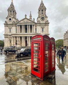 a red phone booth sitting in the middle of a street