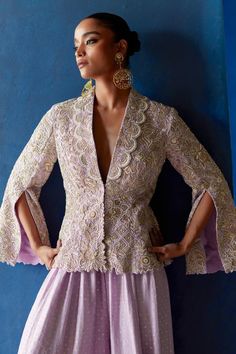 Lilac shawl collar jacket with off-white resham, pearl and zardozi embroidery all over. Paired with a gathered palazzo with sequins texture and off-white resham, pearl and zardozi embroidery at the hemline. Components: 2 Pattern: Embroidery Type Of Work: Resham, Zardozi, Pearls, Sequins Neckline: Shawl Collar Sleeve Type: Split Sleeves Fabric: Jacket: Raw Silk, Palazzo: Pure Silk Color: Purple Other Details:  Scallop trimmed neckline Occasion: Destination Wedding - Aza Fashions Mrunalini Rao, Shawl Collar Jacket, White Party Outfit, Haldi Outfits, Wedding Lehenga Designs, Zardozi Embroidery, Simple Kurti Designs, Fashion Top Outfits