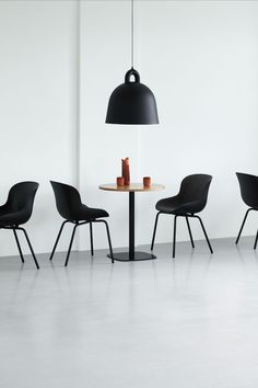 three chairs and a table with a lamp on it in front of a white wall