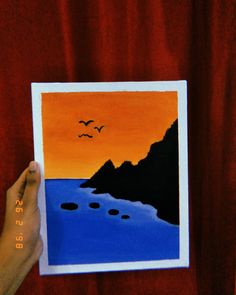 a person holding up a painting with birds flying over the water