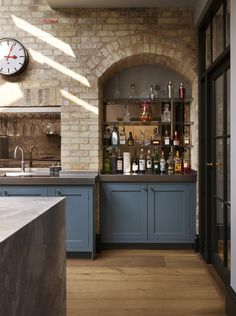 a kitchen with blue cabinets and a large clock on the wall above the bar area