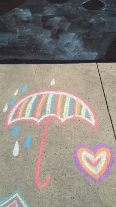 an umbrella and hearts drawn in chalk on the sidewalk