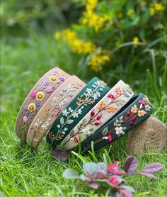 several bracelets are laying on the grass in front of some flowers and plants,