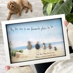 a person holding up a card with three birds on the beach in front of them