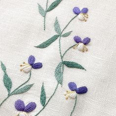 some purple and white flowers are on a piece of cloth with green stems in the middle