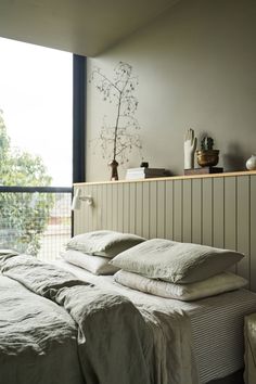 a bed with white sheets and pillows next to a window