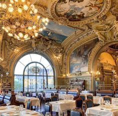 an ornately decorated dining room with chandeliers and paintings on the walls, along with white tablecloths