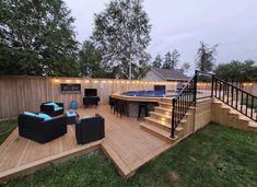 a deck with chairs, couches and lights on the stairs leading up to a hot tub