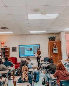 several people are sitting in chairs and watching a presentation on a large screen while others sit at their desks