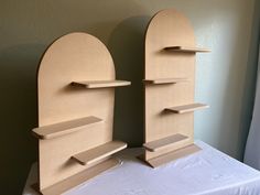 two wooden bookshelves sitting on top of a white table next to each other