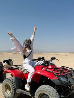 a man riding on the back of an atv with his arms up in the air