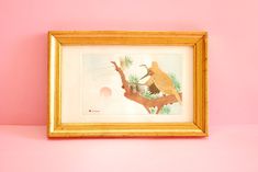 an image of two birds on a branch in a gold frame against a pink wall