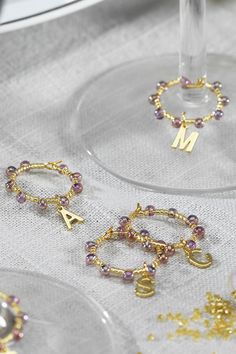 three wine glasses filled with different types of beaded bracelets and charms on top of a table